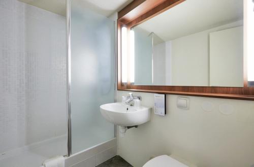 La salle de bains est pourvue d'un lavabo, d'un miroir et de toilettes. dans l'établissement Campanile Toulon - La Seyne sur Mer - Sanary, à Six-Fours-les-Plages