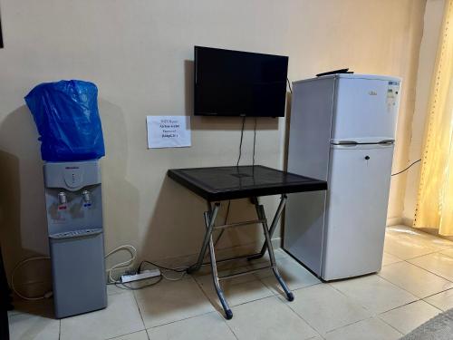 a desk and a refrigerator and a table with a television at DeadSea Accommodation with AC in Sowayma