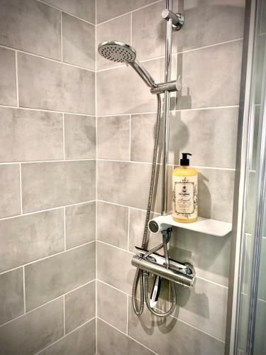 une douche avec pommeau de douche dans une salle de bain dans l'établissement L indémodable rénové spacieux et lumineux avec 2 chambres, à Sarrebourg