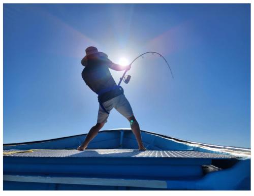 a man standing on top of a boat holding a rod at Casa Kayack in San Carlos