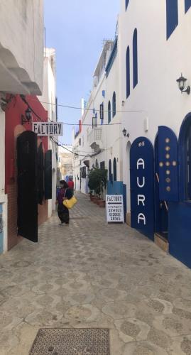 a woman walking down a street with a sign on a building at Appartement haut standing jardins Assilah in Asilah