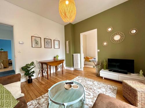 uma sala de estar com uma mesa e uma televisão em Appartement entier en plein coeur du centre ville em Compiègne