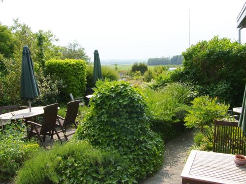 a garden with tables and chairs and green umbrellas at Klintholm B & B Bistro in Borre