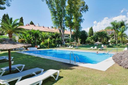 una piscina con sillas blancas y un complejo en Suite Puerto Banus con piscina, en Marbella