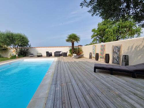 - une piscine sur une terrasse en bois à côté d'une maison dans l'établissement Villa avec Piscine à 15 min de La Rochelle, Proche Plages et Commerces - FR-1-706-13, à Angoulins-sur-Mer