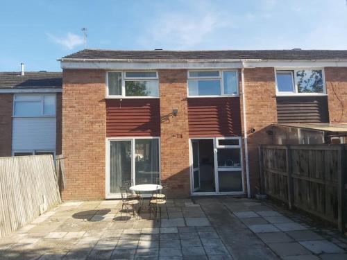 a brick house with a patio and a table at 3 bedrtoom comfortable house in Houghton Regis