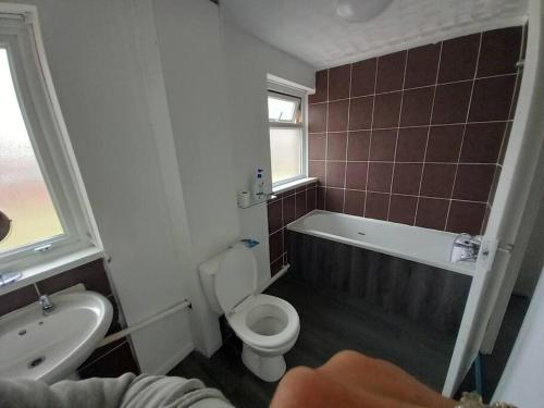 a bathroom with a toilet and a tub and a sink at 3 bedrtoom comfortable house in Houghton Regis