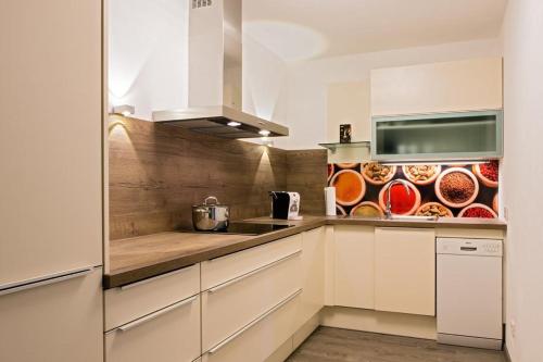 una cocina con armarios blancos y una barra con platos en Apartment Schafbergblick mit Balkon ID 8607747 und Apartment Himmelspforte mit Balkon ID 8607779 en Mondsee