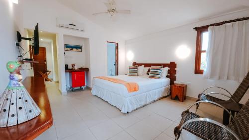 a bedroom with a bed and a table and a chair at Pousada João Fernandes in Búzios