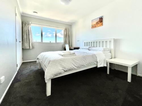 a white bedroom with a large bed and a window at Albany Modern Private 2 bedroom 2 bathroom with Full Kitchen Netflix in Auckland