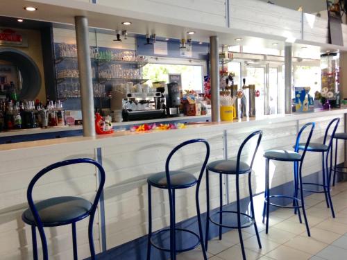 a bar with four blue stools in a restaurant at Camping Le Walric in Saint-Valery-sur-Somme