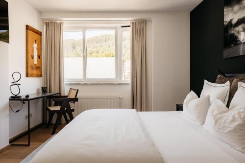 una camera con letto bianco, scrivania e finestra di The Edgewater Suites - Park View a Namur