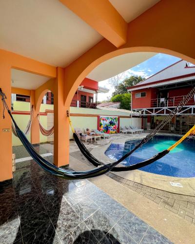 a hammock in the courtyard of a house with a pool at Hostel de Haan in Jacó