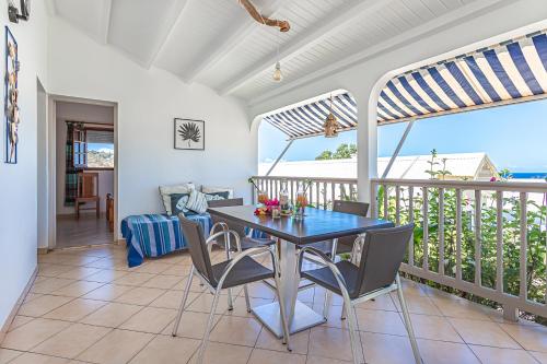 a dining room with a table and chairs on a balcony at Résidence Pommes Cannelles in Bouillante