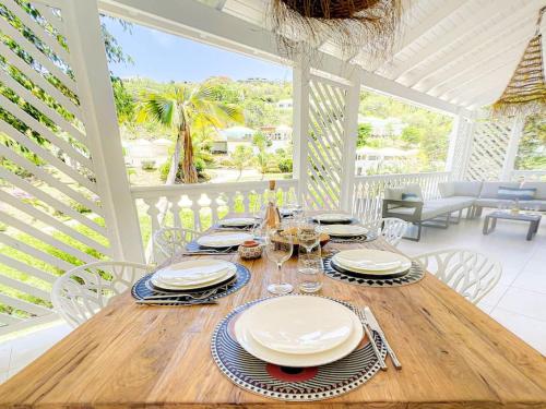 un tavolo in legno con piatti e bicchieri da vino su un portico di Villa Bulle clothing optional around the prival pool a Orient Bay