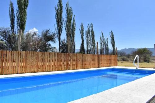 una piscina azul con una valla de madera en Cabaña Finca el Oasis en Jáchal, San Juan en San José de Jáchal