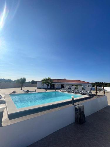 a swimming pool with chairs and a building at Alojamento do Monte in Estremoz