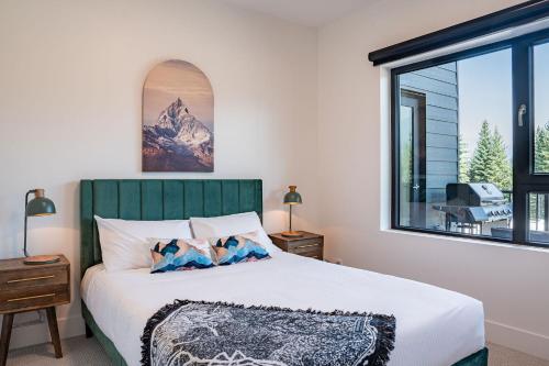 a bedroom with a bed and a large window at Slopes and Greens by Revelstoke Vacations in Revelstoke