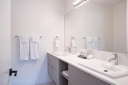 a white bathroom with two sinks and a mirror at Slopes and Greens by Revelstoke Vacations in Revelstoke