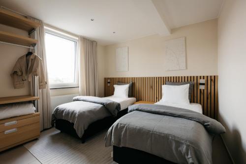 a bedroom with two beds and a window at The Edgewater Suites - SKYLINE in Namur
