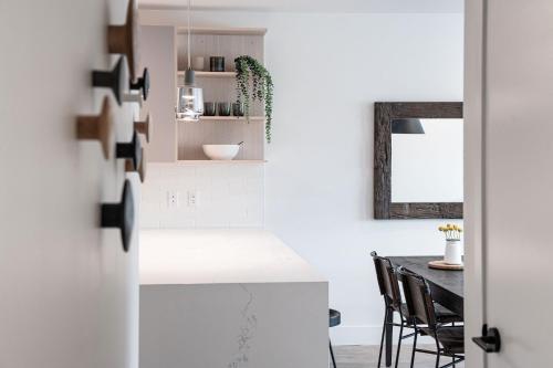 a kitchen with white counters and a table with chairs at The Monashee House by Revelstoke Vacations in Revelstoke