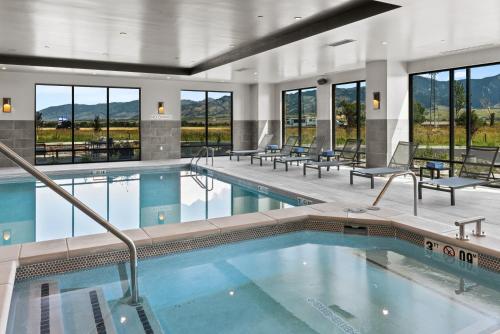 a pool in a hotel with tables and chairs and windows at Courtyard by Marriott Bozeman in Bozeman