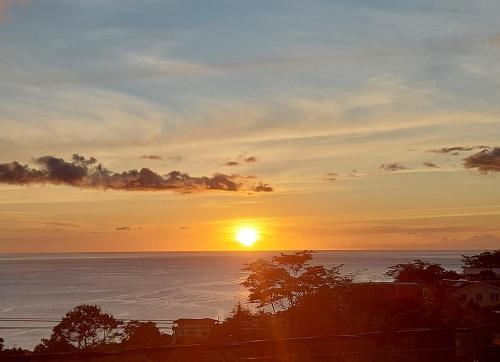 una puesta de sol sobre el océano con el sol en el cielo en Sea View Guest Accommodation, en Roseau