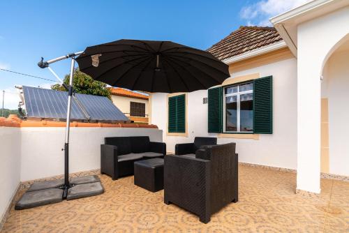 a patio with an umbrella and chairs and a table at Noite´s House - Prazeres in Prazeres