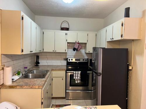 a kitchen with white cabinets and a black refrigerator at Tropical Hideaway in Nassau