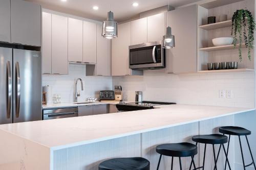 a kitchen with white cabinets and black bar stools at The Selkirk House by Revelstoke Vacations in Revelstoke