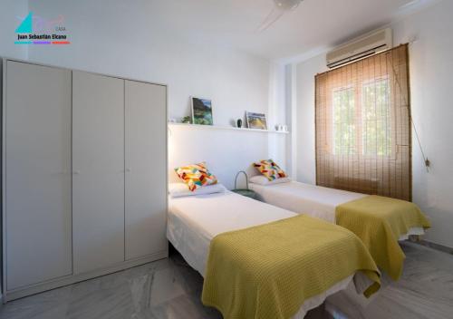 two beds in a room with white walls and a window at Casa Juan Sebastian Elcano in Gelves