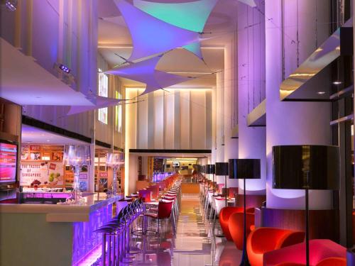 a restaurant with a bar with red chairs and purple lighting at Ibis Singapore on Bencoolen in Singapore