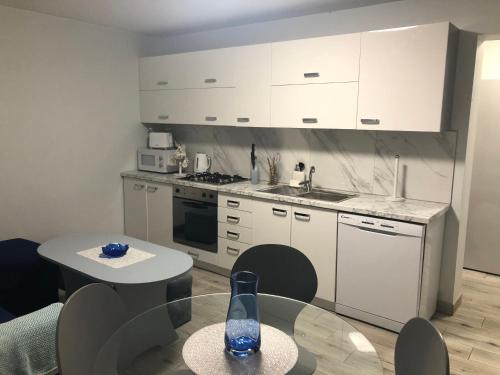 uma cozinha com armários brancos e uma mesa com uma garrafa em Apartament Guziczek em Nowy Targ