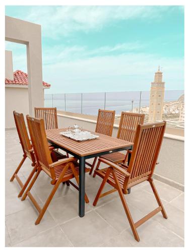 a wooden table and four chairs on a balcony at Appartement de luxe Al hoceima in Al Hoceïma