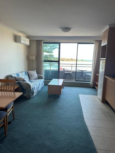a living room with a couch and a table at A-The Entrance Private Water Front 1 bedroom appartment at the Oaks in The Entrance