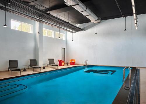 a pool in a room with chairs and a swimming pool at Aloft Leawood-Overland Park in Overland Park