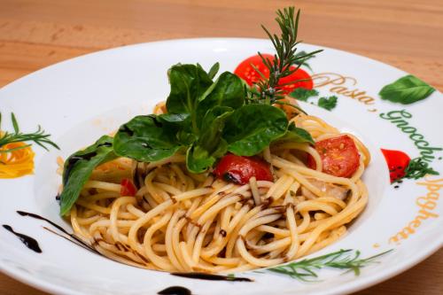 a plate of pasta with tomatoes and greens on a table at Landgasthof Zur Erholung in Breitscheid
