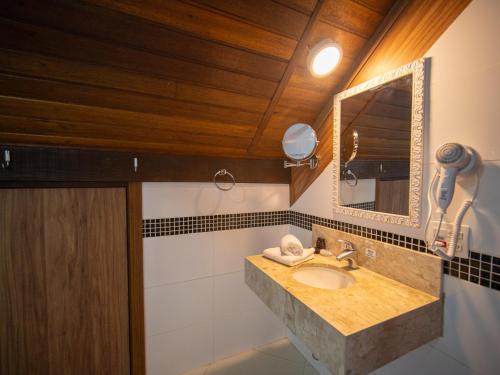 a bathroom with a sink and a mirror at Pousada Suiça Mineira Centro in Monte Verde