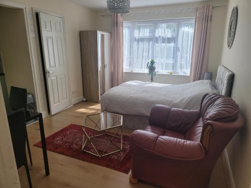 een slaapkamer met een bed, een bank en een stoel bij Lovely studio flat in Reading