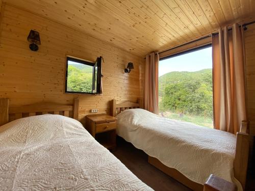 2 łóżka w drewnianym pokoju z oknem w obiekcie Cozy cabin w mieście Tbilisi City