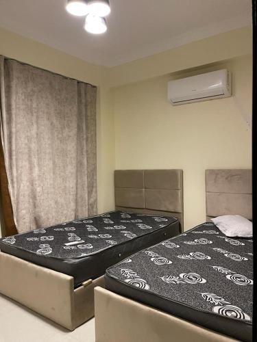 1 dormitorio con 2 camas y ventana en فيلا بقريه فرح ٢ الساحل الشمالي en El Alamein