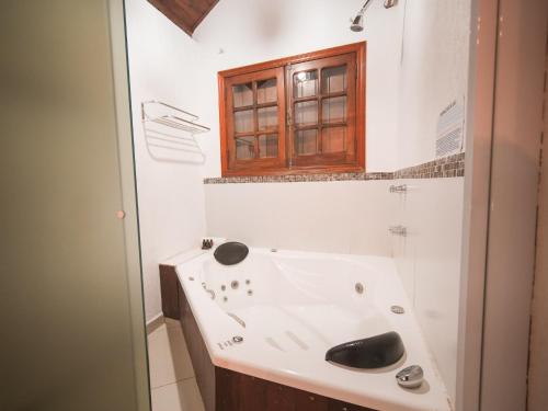 a bathroom with a white sink and a window at Pousada Suiça Mineira Centro in Monte Verde