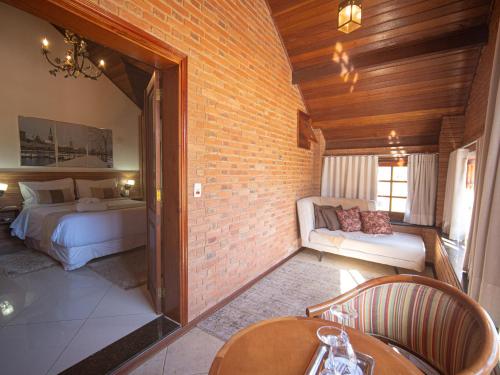 a bedroom with two beds and a brick wall at Pousada Suiça Mineira Centro in Monte Verde
