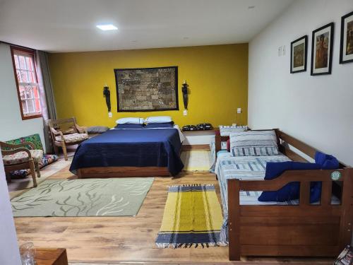um quarto com 2 camas e uma parede amarela em Solar dos Reis Apartamento Topázio em Ouro Preto