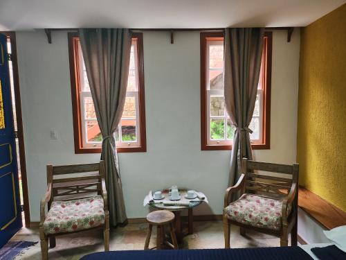 two chairs and a table in a room with windows at Solar dos Reis Apartamento Topázio in Ouro Preto