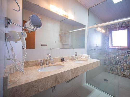 a bathroom with a sink and a mirror and a shower at Pousada Suiça Mineira Centro in Monte Verde