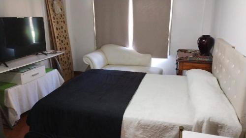 1 dormitorio con 1 cama, TV y silla en Casa Quinta con pileta Tortuguitas Bs As en Manuel Alberti