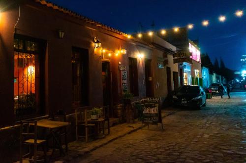 Humahuaca Hostel في هوماهواكا: شارع بالحصى فيه مطعم ومباني بالليل