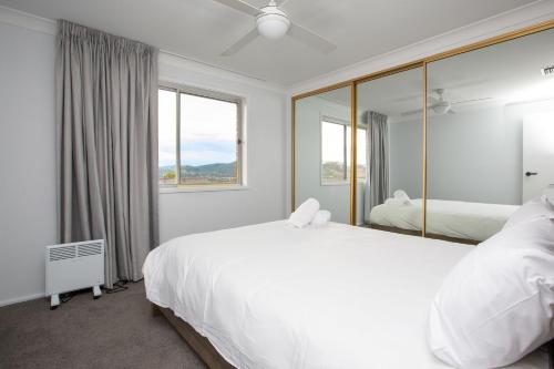 1 dormitorio con 1 cama blanca grande y espejo en Hillvue Lodge, en Tamworth