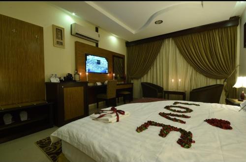 賴斯的住宿－شقق النخيل，酒店客房的床铺上摆放着玫瑰花